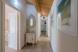Ein Flur mit Holzbalkendecke, einer weißen Tür, einem Waschtisch mit Spiegel und einem gerahmten Bild an der Wand.