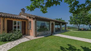 A single-story house with a tiled roof, large windows, and a covered patio area.