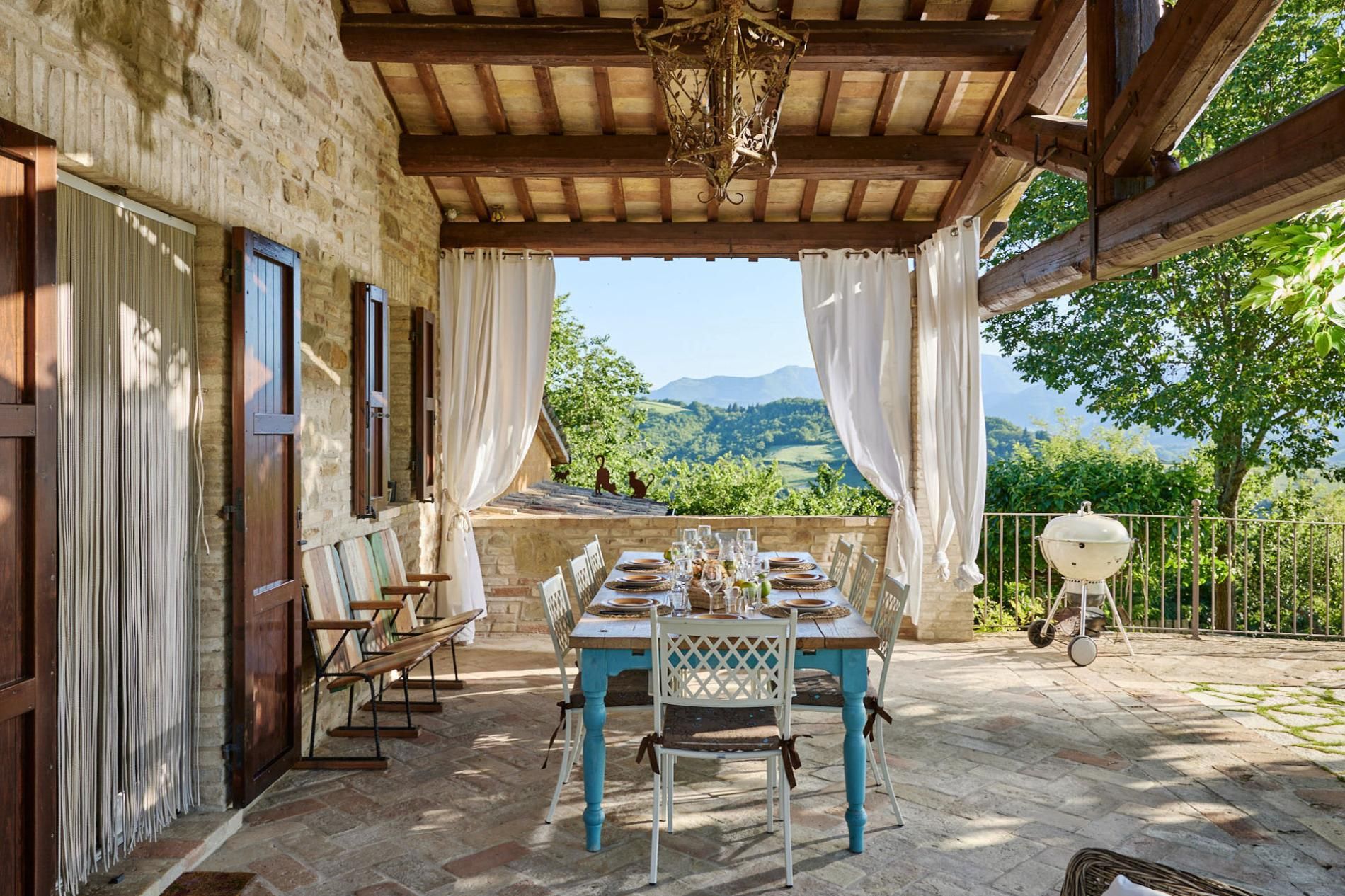 Un espace de restauration en plein air avec une table dressée pour quatre personnes, offrant une vue sur un paysage montagneux.