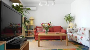 A living room with a flat-screen TV, a red sofa, a wooden coffee table, and a colorful rug. - AIR CONDITIONING, FREE WIFI, NE TFLIX, ONLY 2 MINUTES BEACH (Alicante)