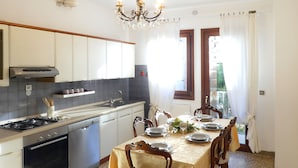Een keuken met een eettafel voor zes personen, een kroonluchter en uitzicht door het raam.