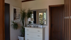 A room with a white dresser, a mirror, a potted plant, and a door. - Villa with private pool in Pinar de los Franceses (WIFI) (Chiclana De La Frontera)