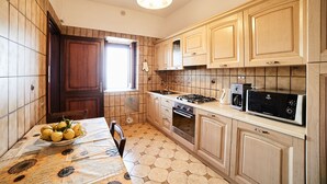A kitchen with wooden cabinets, a stove, an oven, a microwave, and a window. - Apt Emma in Villa Laura near Ravello (scala)