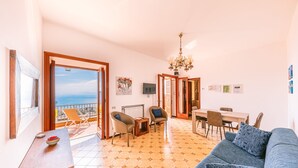 A spacious living area with a balcony, a dining table, and a sofa. - Apt Emma in Villa Laura near Ravello (scala)