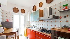 Et køkken med gaskomfur, ovn og moderne skabe. Der er et spiseområde med et bord og stole.