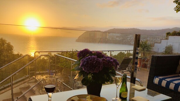 A balcony with a glass table, a chair, a bottle of wine, and a bowl of olives. - Casa Valderrama - Beautiful Spacious Villa With Private Pool And Hot Tub.  (La Herradura)