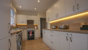 A modern kitchen with white cabinets, stainless steel appliances, and a wooden countertop.