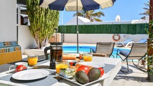 A breakfast setup with a table, umbrella, and poolside view. - Villa with private pool and free wifi (Tías)