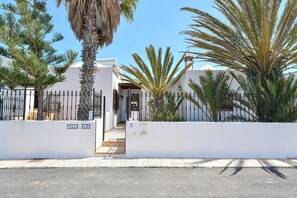 A gated villa complex with white walls and a palm tree.
