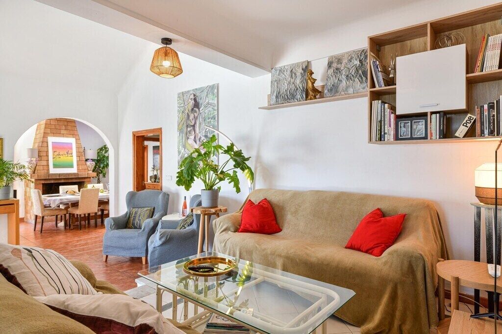 A cozy living room with a sofa, armchairs, a glass coffee table, and a fireplace.