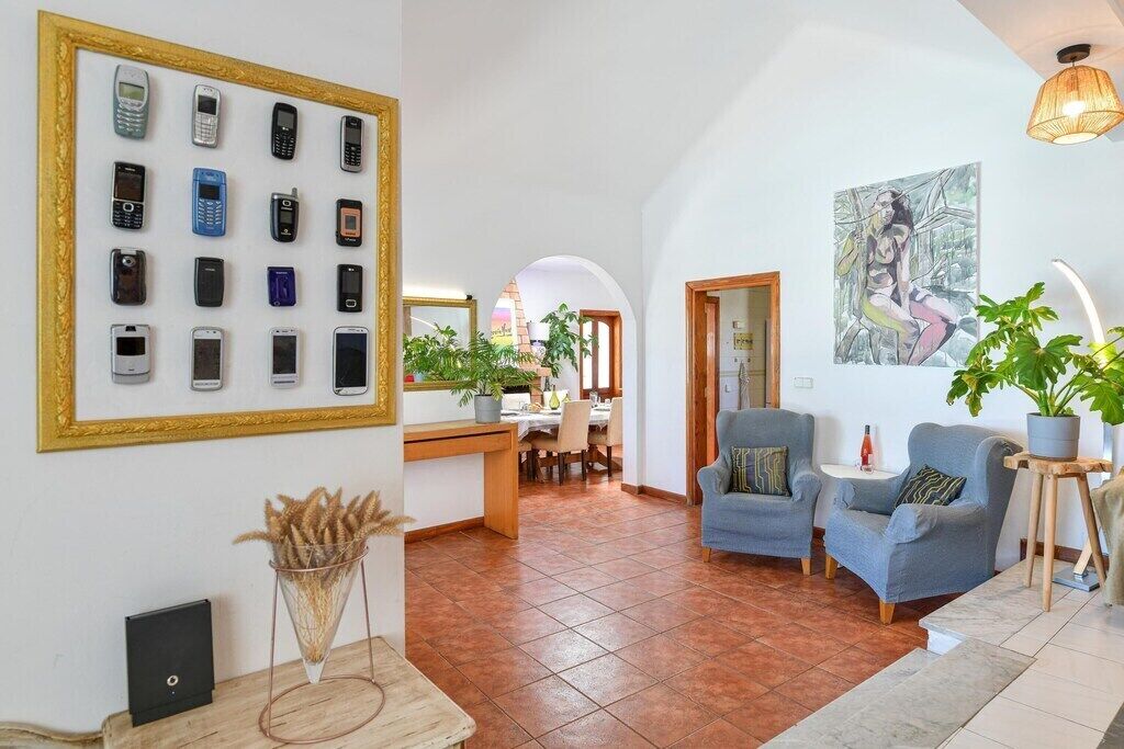 A spacious living area with a dining area, a framed collection of mobile phones on the wall, and a painting on the wall.