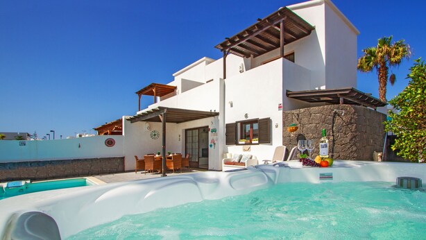 Une maison moderne dotée d’une piscine, d’un espace salon extérieur et d’un mur en pierre.