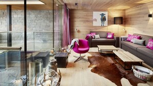 Ein modernes Wohnzimmer mit einem Glastisch, einer Ledersofa und einem leuchtend rosafarbenen Sessel.