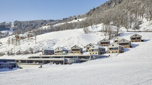 Ein schneebedecktes Skigebiet mit modernen Holzhäusern und einem Glasgebäude mit der Aufschrift 'Rodevertbahn'.