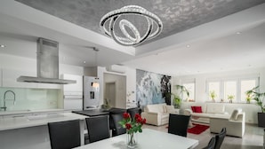 A modern kitchen with a central island, dining area with chairs, and a living room with a sofa and plants. - Luxury villa Palladium in the center with * heated pool, * penthouse and * whirlp. (Makarska)
