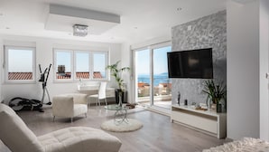 A modern living room with a large TV, comfortable seating, a view of the sea, and a balcony with exercise equipment. - Luxury villa Palladium in the center with * heated pool, * penthouse and * whirlp. (Makarska)