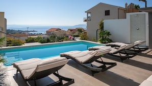 A swimming pool with lounge chairs, a view of the sea, and a building with a balcony. - Luxury villa Palladium in the center with * heated pool, * penthouse and * whirlp. (Makarska)