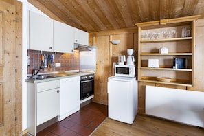 A compact kitchen with white cabinets, a built-in oven, a microwave, and a coffee maker.