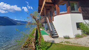 A wooden cabin with a balcony overlooking a lake, surrounded by mountains. - Waterfront Apartment 3 (Zell am See)