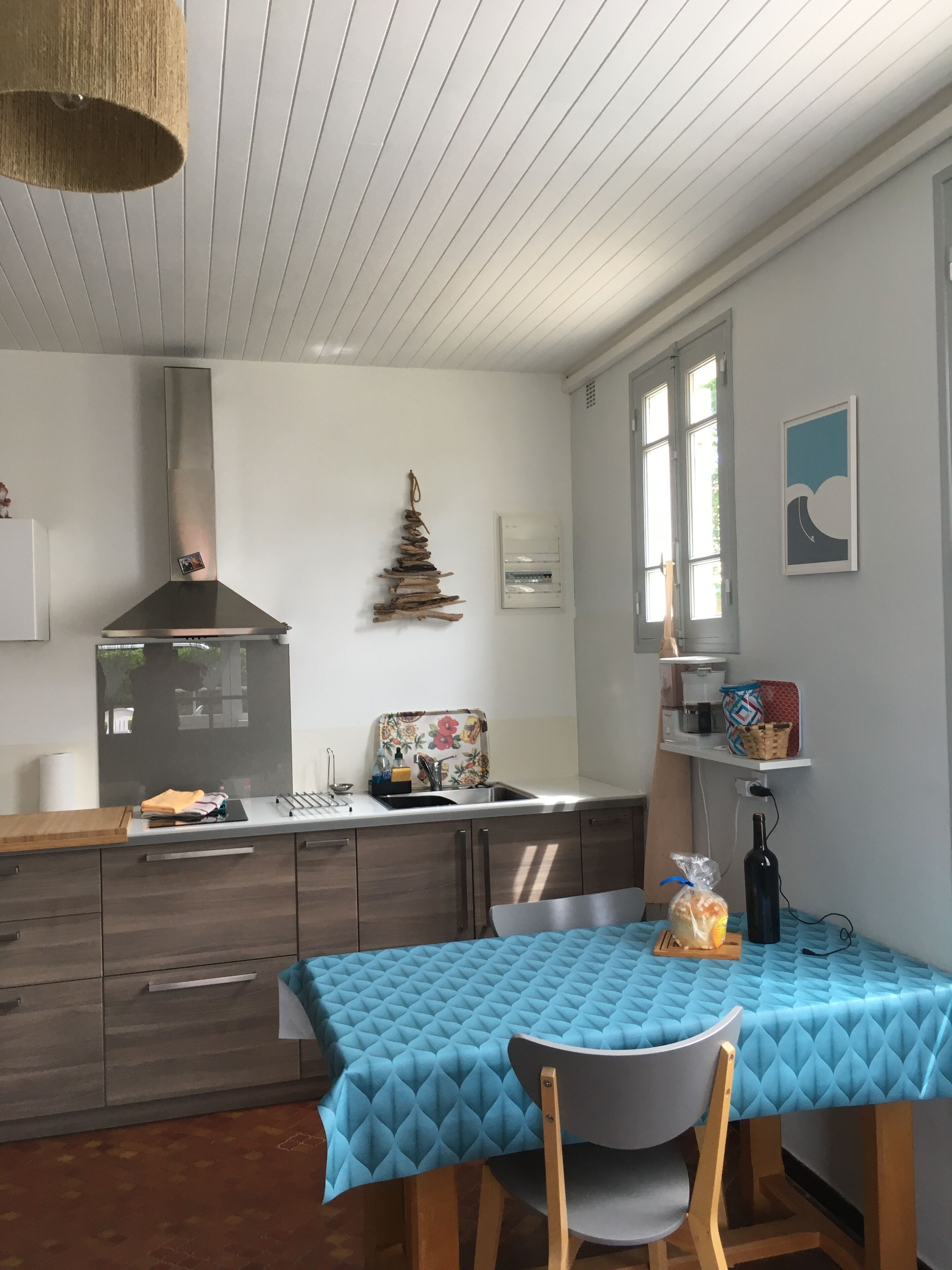 Une cuisine compacte dotée d’une cuisinière moderne, d’un évier et d’un coin repas avec une nappe bleue.