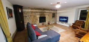 A living room with a stone fireplace, a sofa, a television, and a leather armchair.