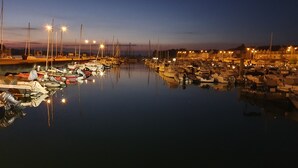 A marina at dusk with boats docked and street lamps illuminating the area. - 17th-century farmhouse with large wooded park - quiet and charming, walking distance to town center and port (Étel)