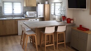 A modern kitchen with a central island, bar stools, a microwave, a refrigerator, and a TV mounted on the wall.