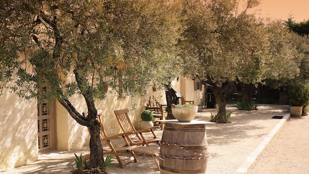 An outdoor seating area with wooden chairs, a large planter, and a barrel.