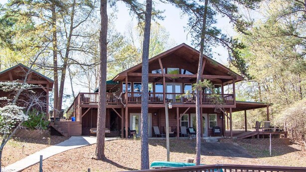A two-story wooden cabin with a balcony, surrounded by trees. - PRIVATE BOAT DOCK AND ONLY 8 STAIRS TO THE WATER (Wedowee)