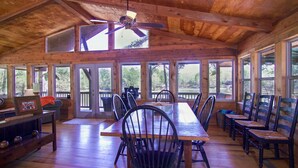 A spacious wooden dining area with a long table and multiple chairs, large windows, and a ceiling fan. - PRIVATE BOAT DOCK AND ONLY 8 STAIRS TO THE WATER (Wedowee)