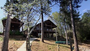 A cabin with a wooden deck and a covered porch, surrounded by trees. - PRIVATE BOAT DOCK AND ONLY 8 STAIRS TO THE WATER (Wedowee)