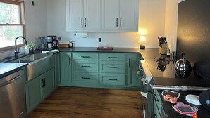 A kitchen with light green cabinets, a wooden floor, a black refrigerator, and a window providing natural light. - PRIVATE BOAT DOCK AND ONLY 8 STAIRS TO THE WATER (Wedowee)
