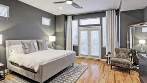 Un dormitorio con cama, una silla, un tocador y un ventilador de techo.