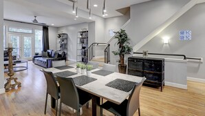 Amplia sala de estar con una mesa de comedor, sillas y una escalera que conduce a un nivel superior.