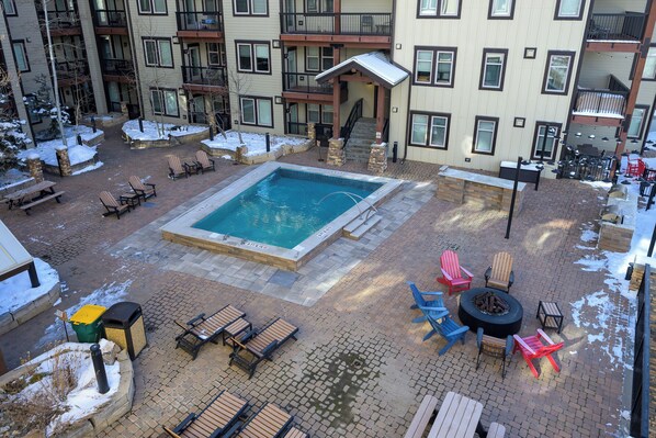 A rooftop pool area with lounge chairs, a fire pit, and a small pool.