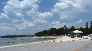 A beach with a sandy shore, a small pavilion, and a few boats in the water.