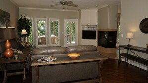 A living room with a leather sofa, a coffee table, a TV, and a ceiling fan.