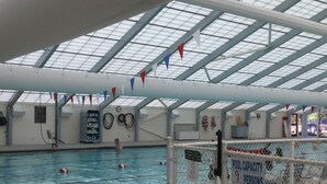 An indoor swimming pool with a capacity sign indicating 9 persons.