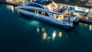 A large yacht docked at a marina with a town in the background.