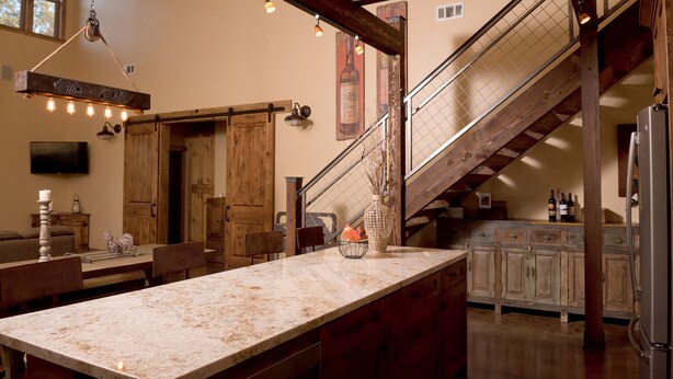 Une cuisine dotée d’un grand îlot central, de meubles en bois et d’un escalier.