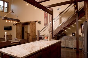 A kitchen with a large island, wooden cabinets, and a staircase.