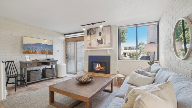 A living room with a fireplace, a sofa, a coffee table, and a TV mounted on the wall.