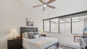 A bedroom with a bed, nightstands, a ceiling fan, a window, and a dresser.
