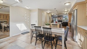 A spacious kitchen with a dining area, featuring a large island, modern appliances, and a view into the living area.