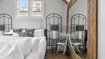Une chambre à coucher avec un lit, deux chaises, un miroir et une fenêtre.