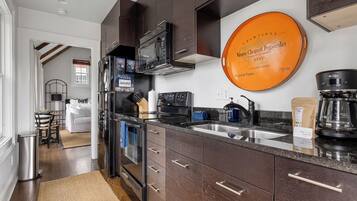 A modern kitchen with dark wood cabinets, a stainless steel refrigerator, a microwave, and a coffee maker.