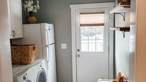 A compact kitchen with a washing machine, a refrigerator, and a dining area with a chair. - ** Close to Sight and Sound Theater<br>Mother's day weekend available  (Ronks)
