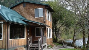Une cabane en bois avec un toit vert, de grandes fenêtres et une véranda.