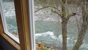 Une vue sur une rivière, avec des rochers et des arbres, depuis une fenêtre.