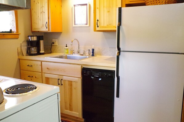 A kitchen with wooden cabinets, a white refrigerator, a Bosch dishwasher, and a stove.